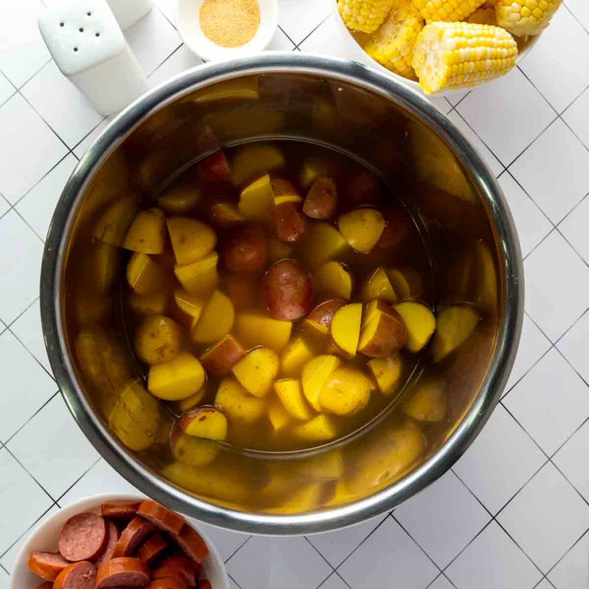Potatoes cooking in broth inside Instant Pot for shrimp boil recipe.