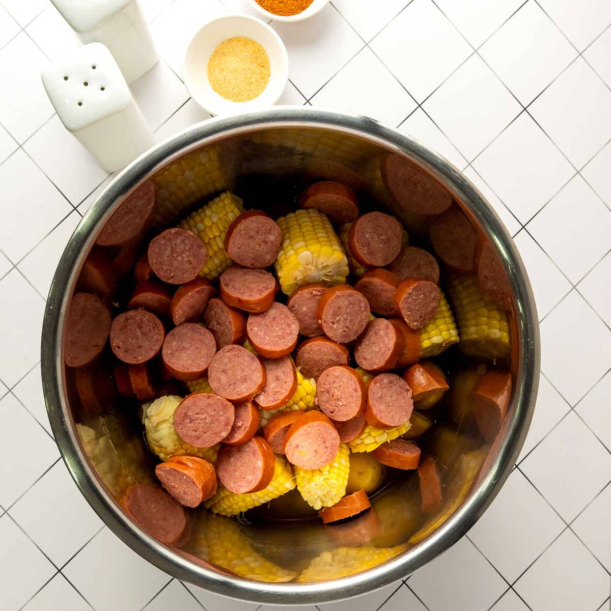 Corn and sliced sausage added to Instant Pot over potatoes.