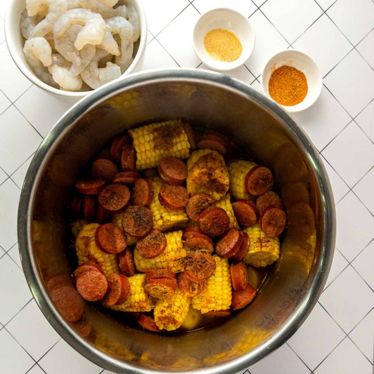 Seasonings sprinkled over corn, sausage, and potatoes in Instant Pot.