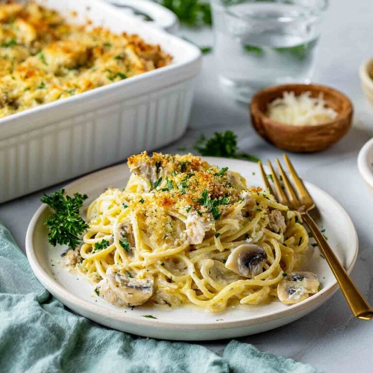A serving of creamy leftover turkey tetrazzini on a white plate with mushrooms and Parmesan crumb topping.