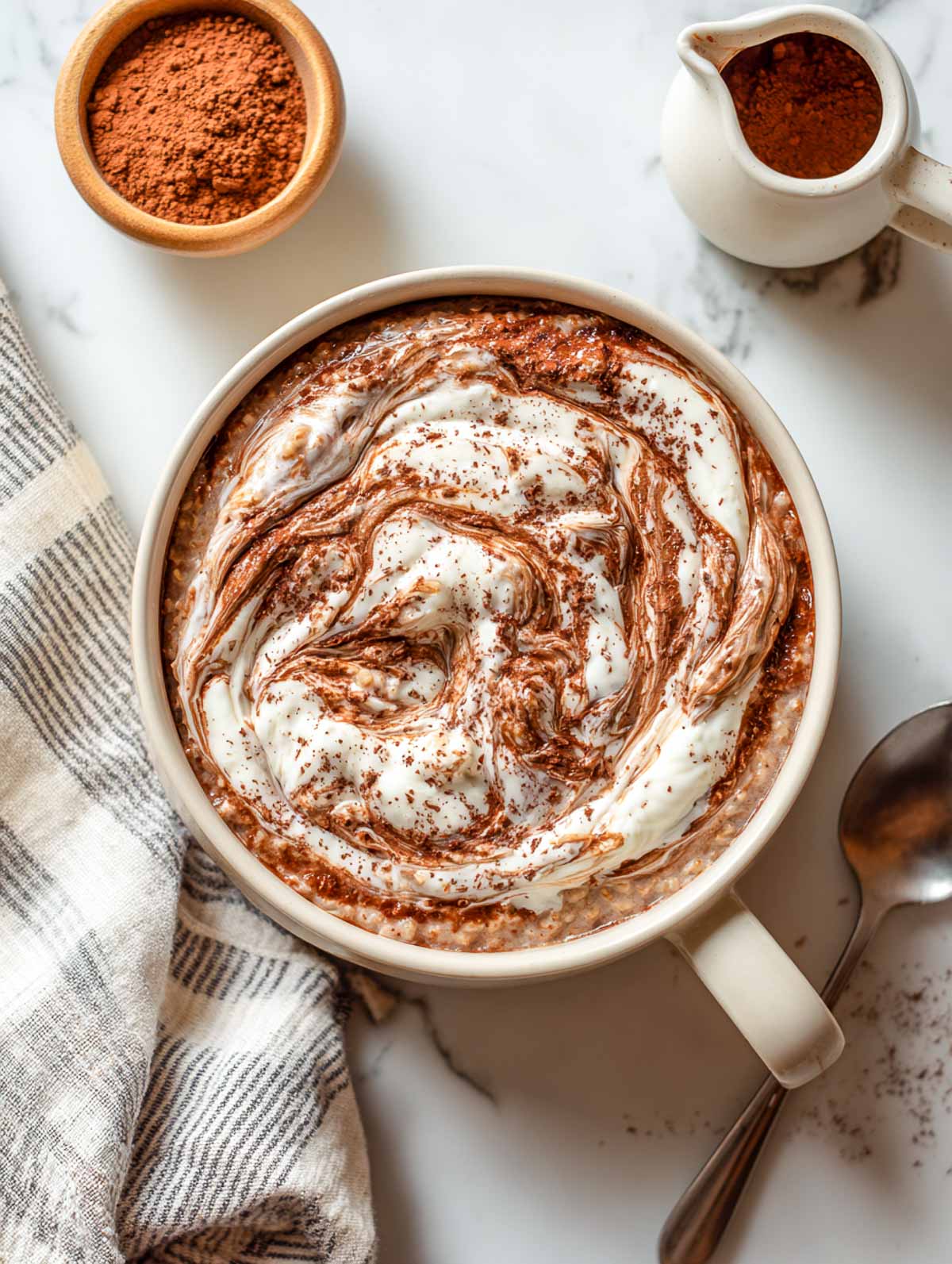 Chocolate oatmeal bowl with creamy cheesecake swirl and cocoa dusting on marble surface.