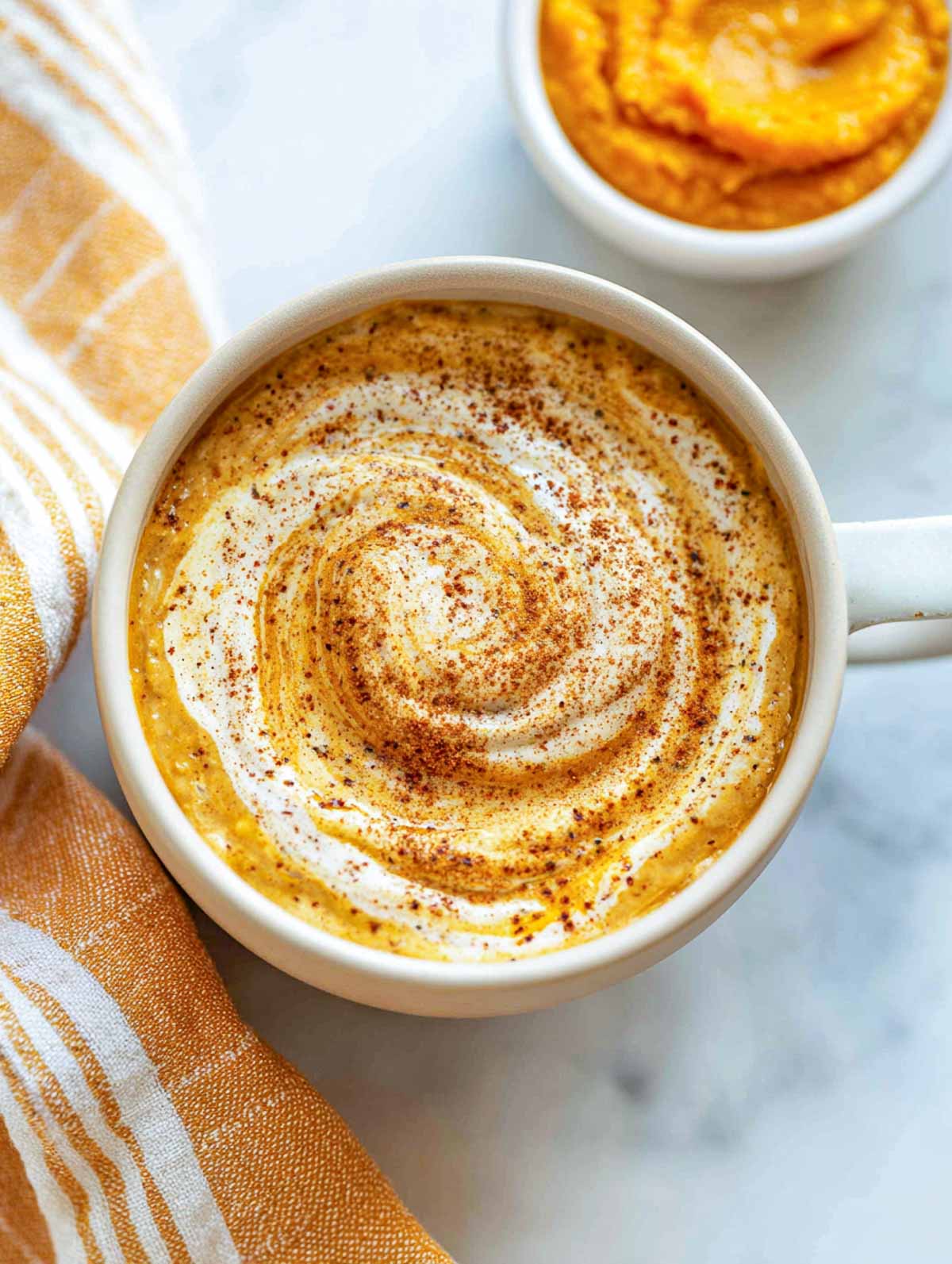 Maple pumpkin oatmeal latte topped with cream swirl and pumpkin spice dusting.