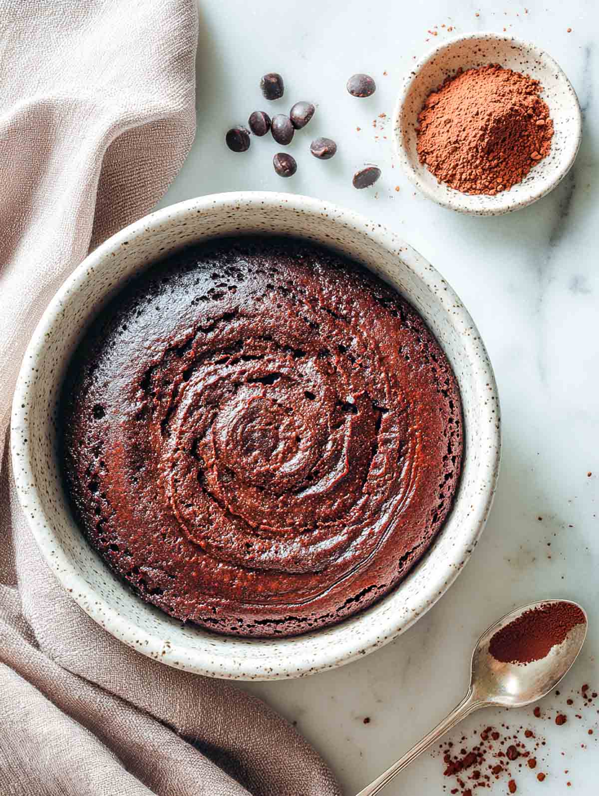 Warm microwave brownie bowl with glossy espresso swirl on marble background.
