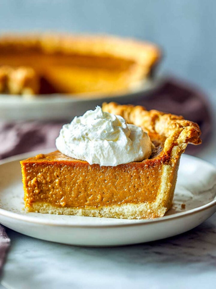 A slice of pumpkin pie served on a white plate.