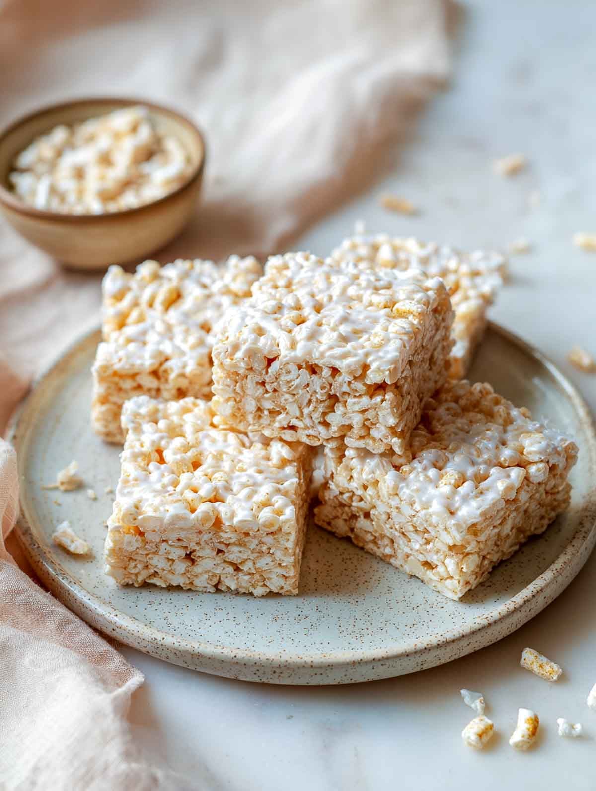 Microwave rice krispie treats cut into soft squares on speckled plate.