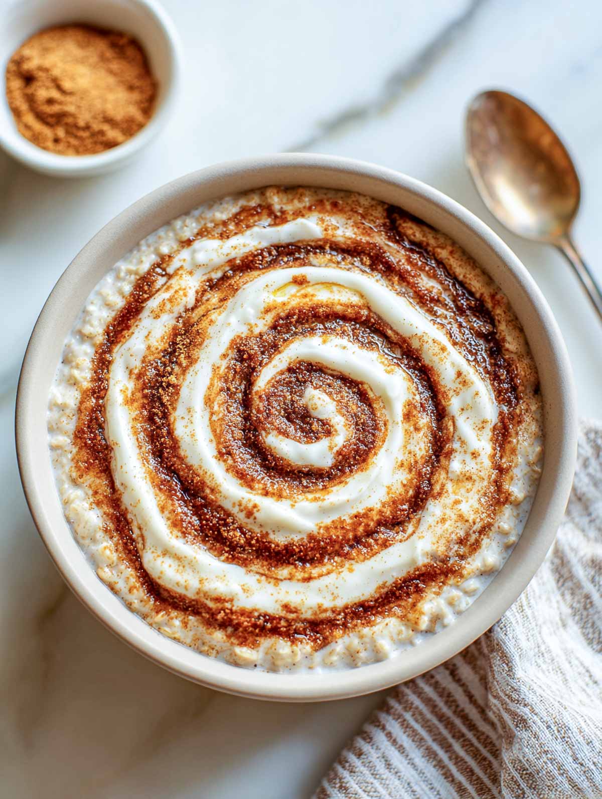Gluten-free cinnamon roll microwave oatmeal topped with cream cheese frosting swirl and cinnamon.