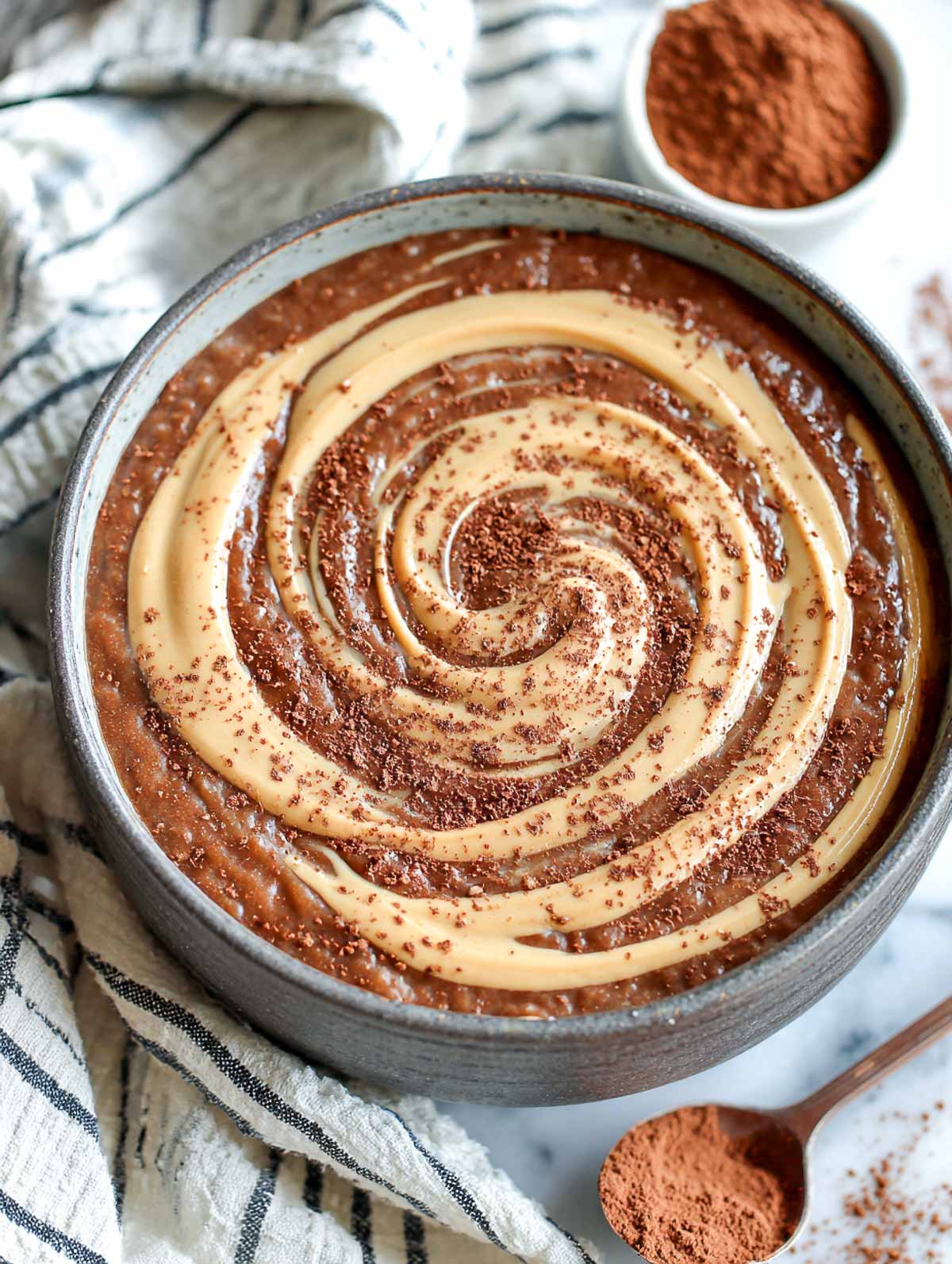 Creamy keto chocolate peanut butter microwave oatmeal topped with swirl and cocoa dust.