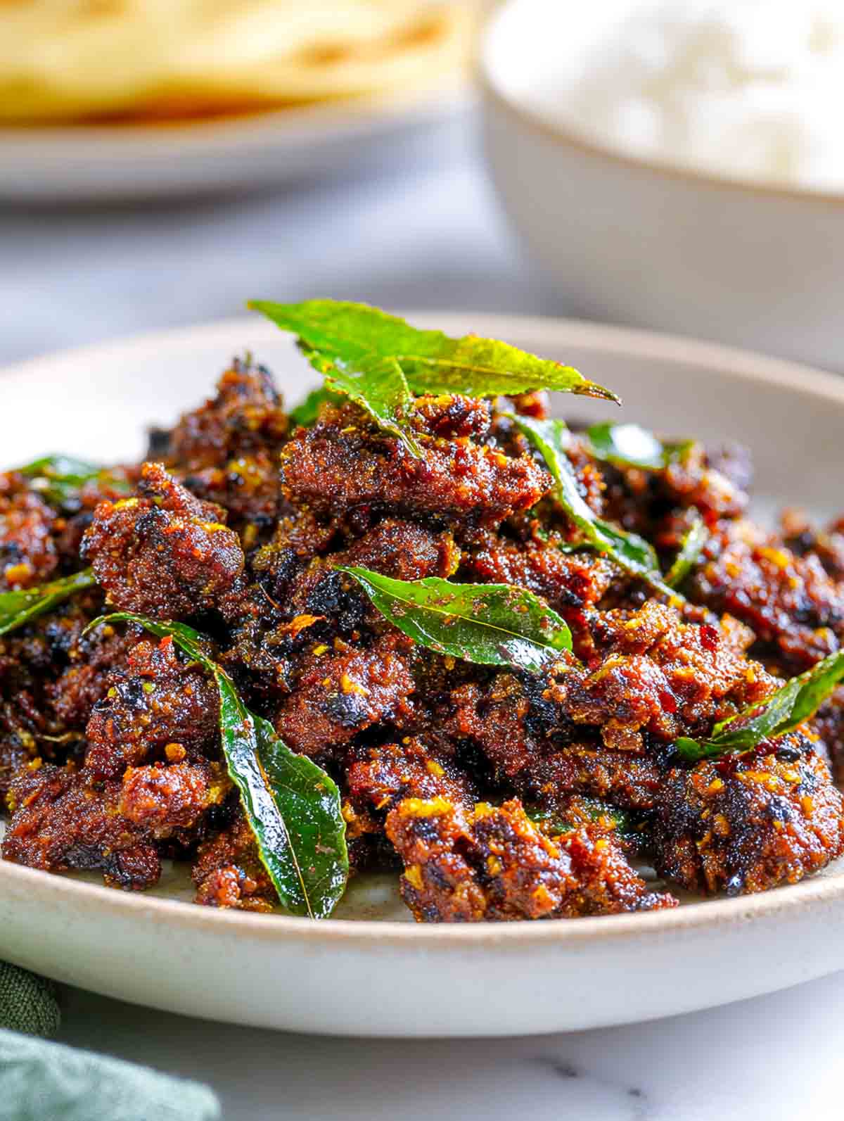 Close-up of crispy lamb pepper fry with toasted spices and curry leaves.