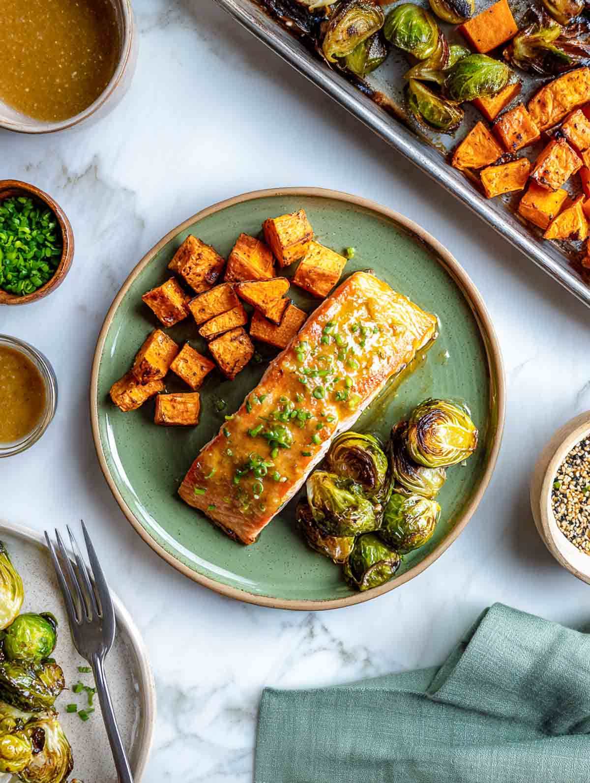 Top down view of maple dijon salmon with roasted brussels sprouts and sweet potatoes on a green plate.