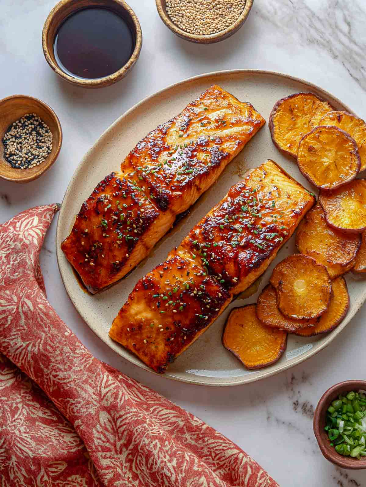 Maple-miso glazed salmon fillets with roasted sweet potato rounds on plate.