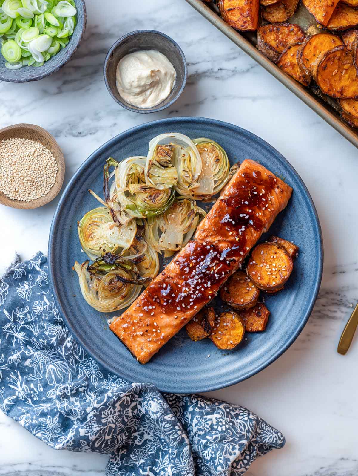 Miso-ginger salmon with roasted sweet potatoes and caramelized leeks on blue plate.