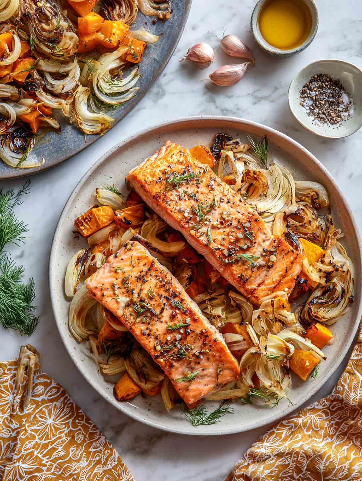 Roasted garlic salmon fillets with sweet potato and caramelized fennel on plate.