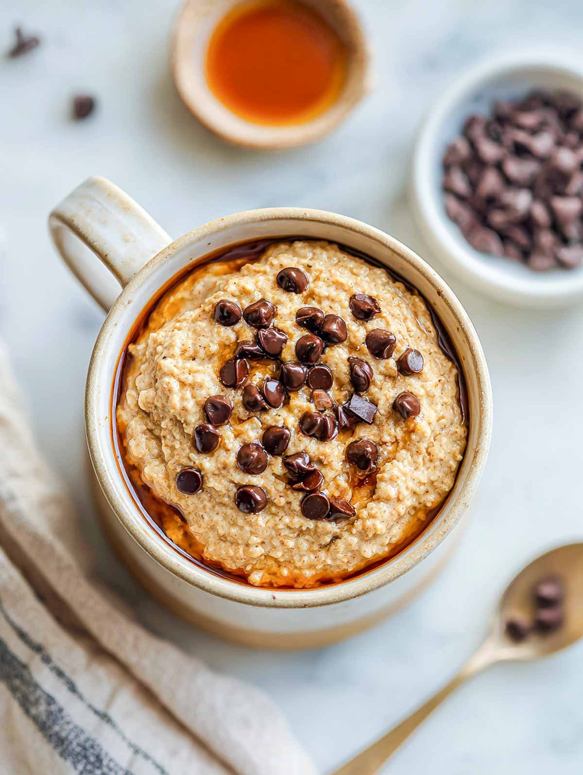 Mug of warm vegan chocolate chip cookie oatmeal topped with melty chocolate chips.