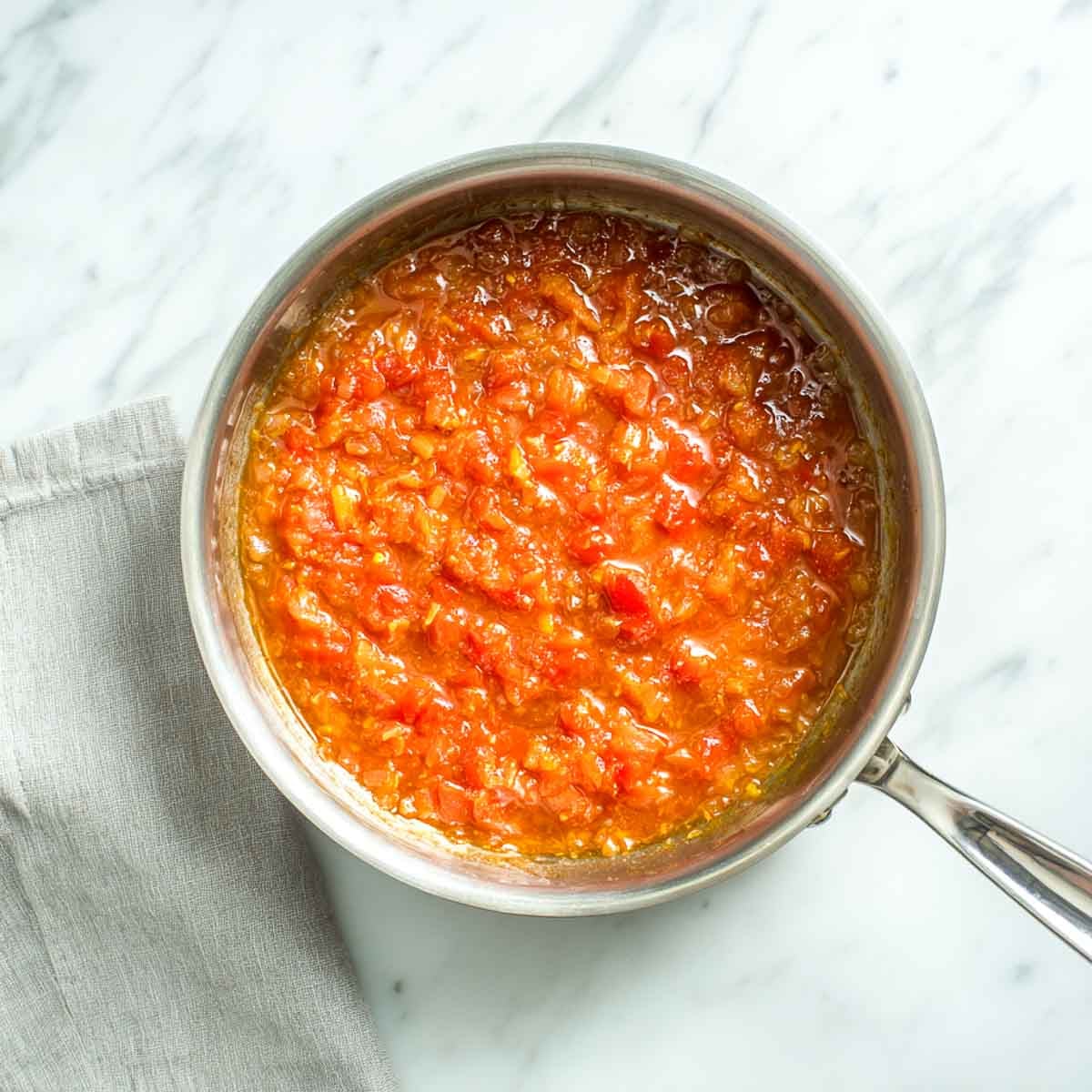 Cooked onion and tomato curry base simmering in a stainless steel saucepan.