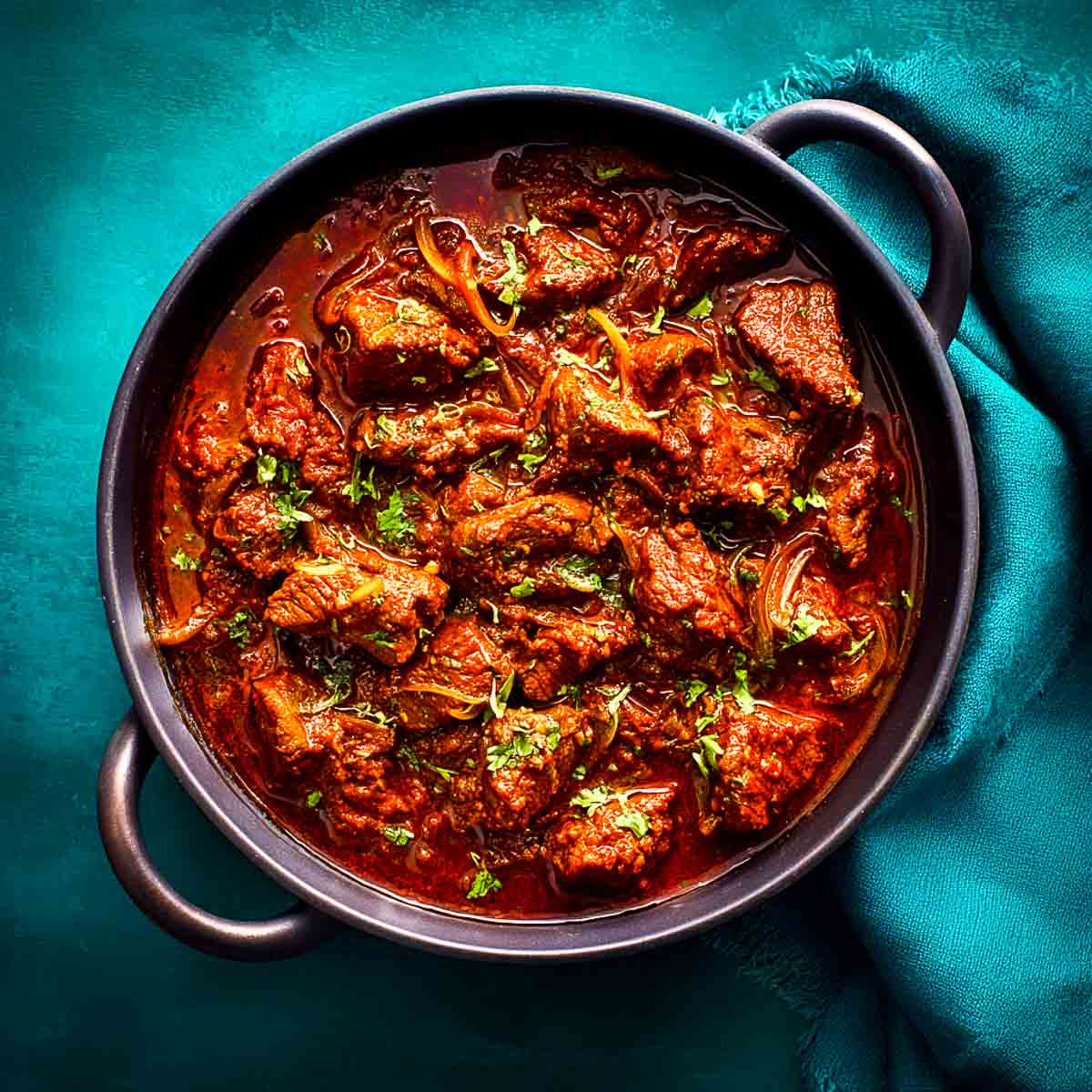 Finished lamb bhuna simmering in a rich, thick sauce with visible oil separation.