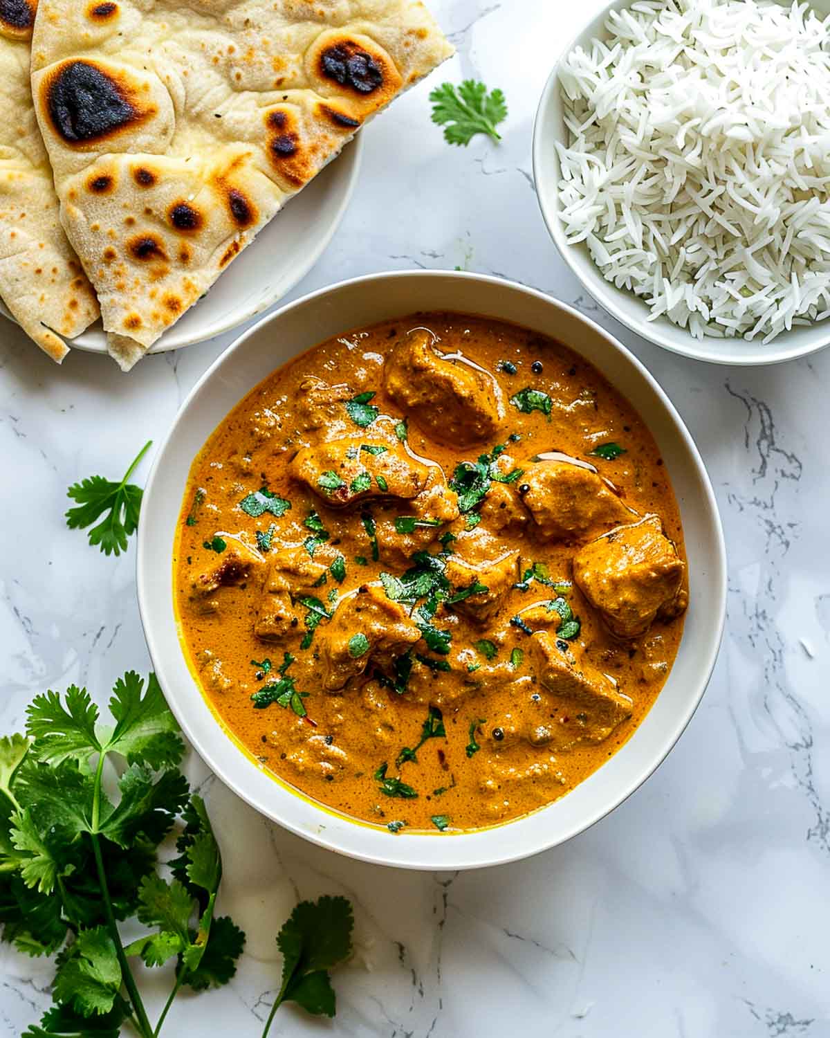 Bowl of creamy lamb korma served with basmati rice and folded naan bread.