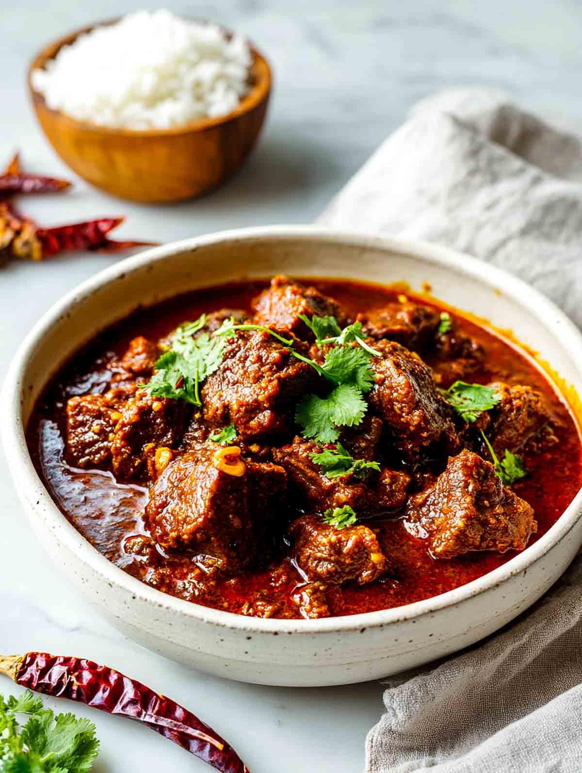 Close up angled view of lamb vindaloo showing tender pieces coated in thick masala.