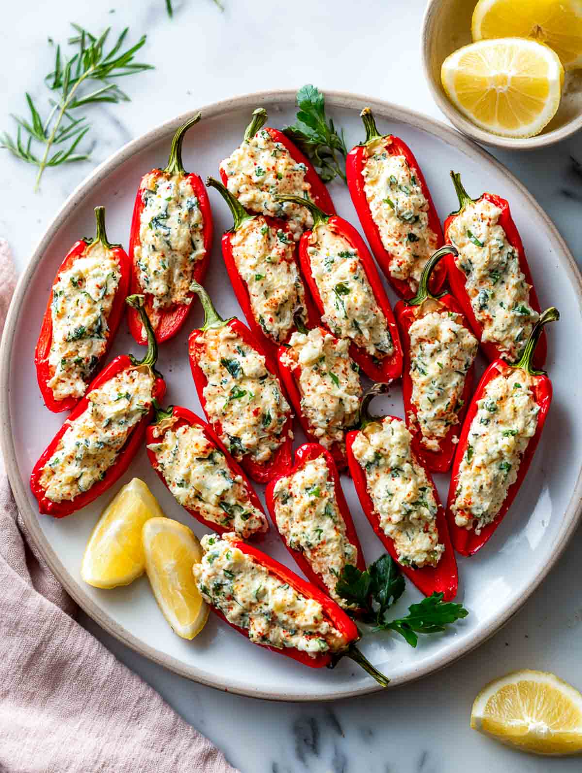 Mini stuffed red peppers filled with creamy lemon feta on a serving plate.
