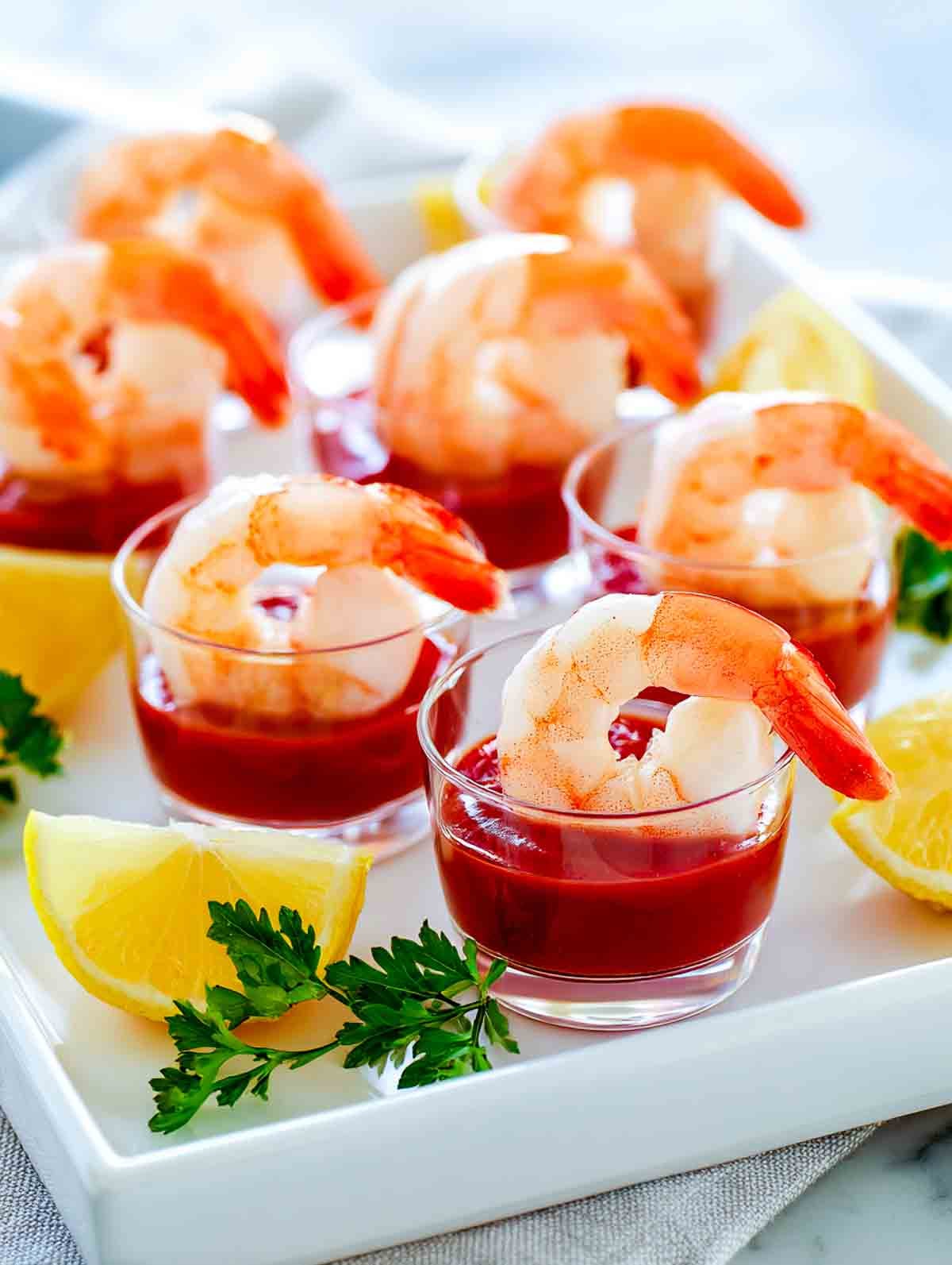 Shrimp cocktail cups with chilled shrimp and cocktail sauce on a serving tray.