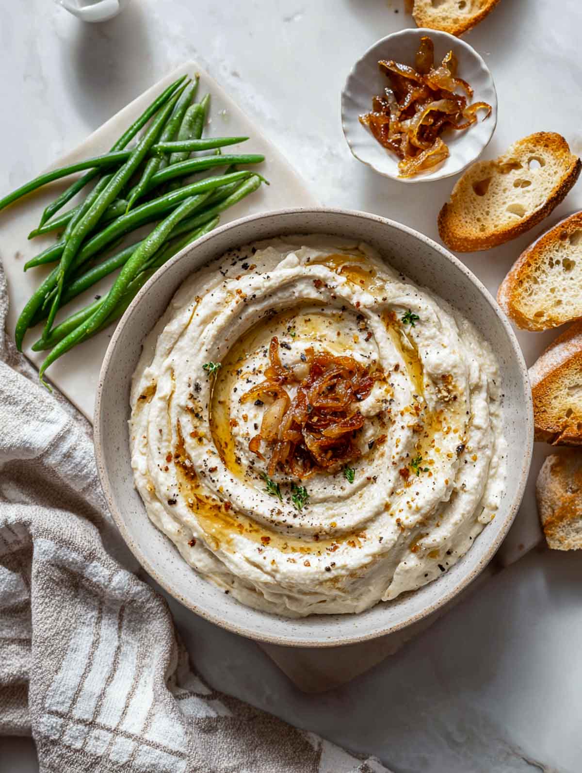 White bean dip topped with caramelized onions and served with bread.
