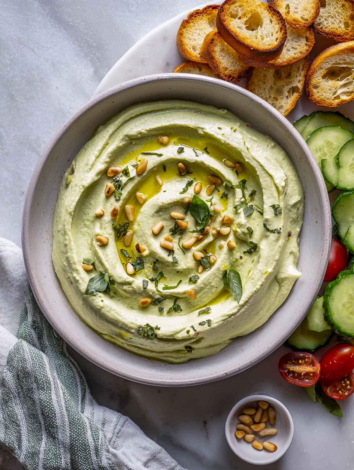White bean pesto dip with basil and pine nuts and bread.