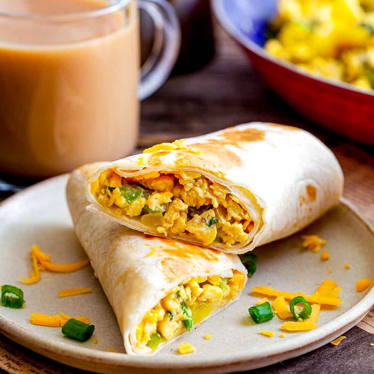 Breakfast burritos filled with scrambled eggs, peppers, cheese on a plate.