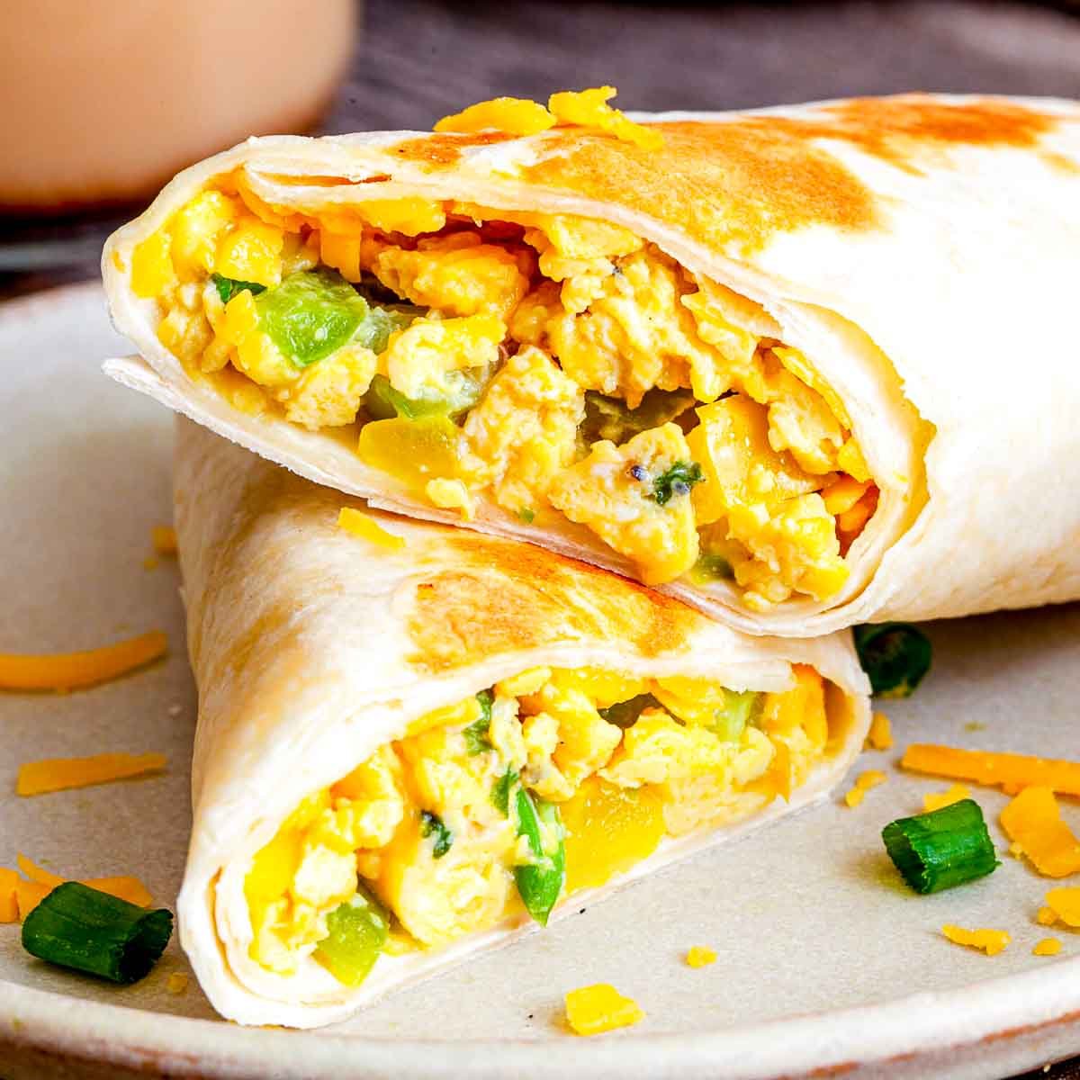 Close-up of breakfast burrito with scrambled eggs, peppers, and cheddar cheese.
