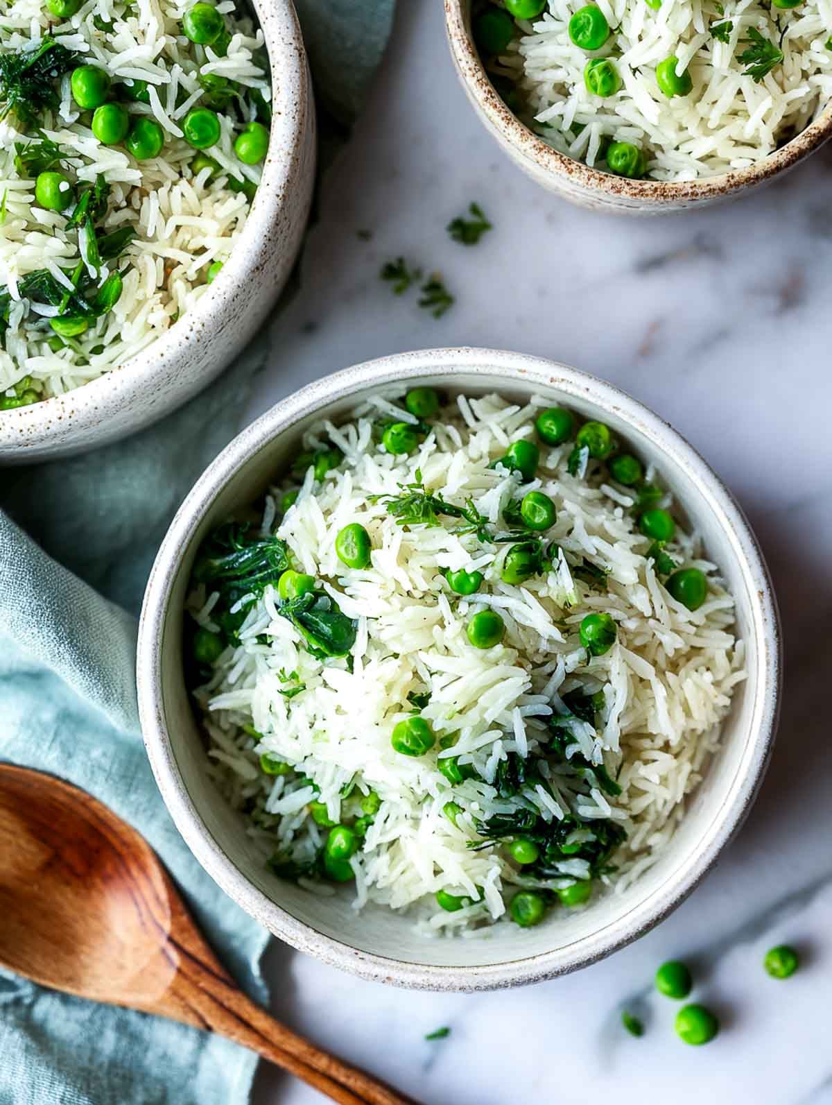 Rice cooker garlic butter rice with spinach and green peas in a ceramic bowl.