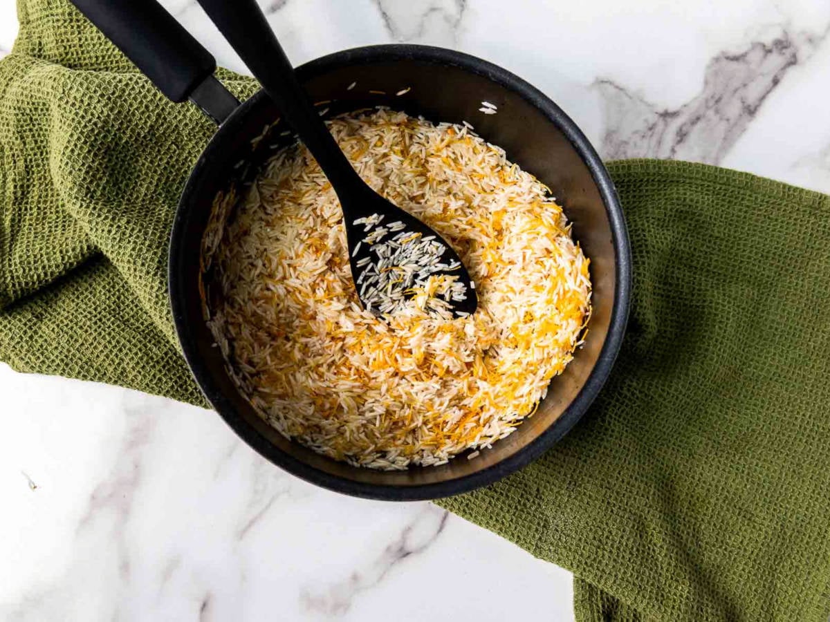 Basmati rice and toasted vermicelli being stirred together in a pot before adding water.