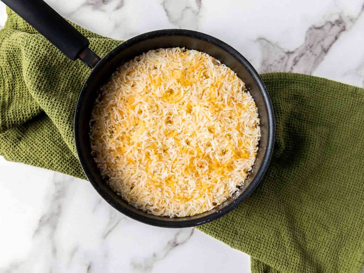 Cooked garlic rice and vermicelli resting in a saucepan, fluffed and ready to be stirred before serving.