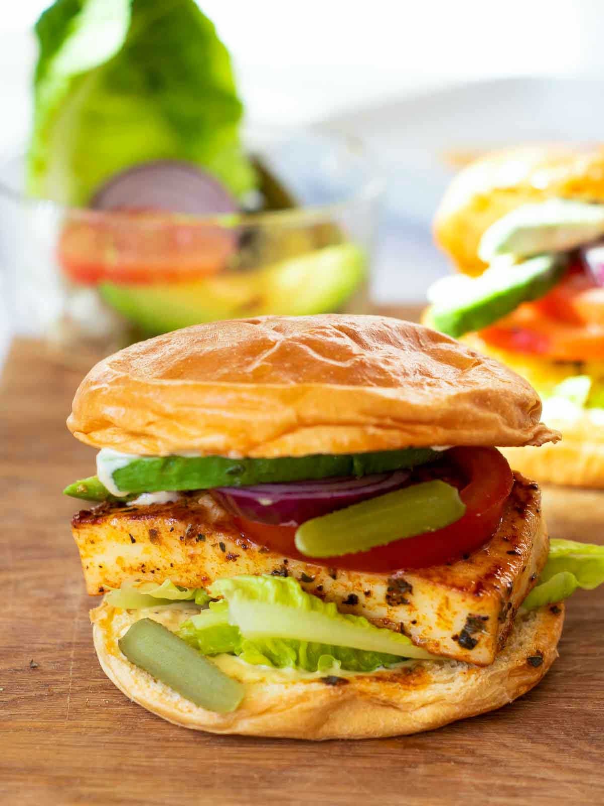 Halloumi burgers assembled and served on a wooden board.