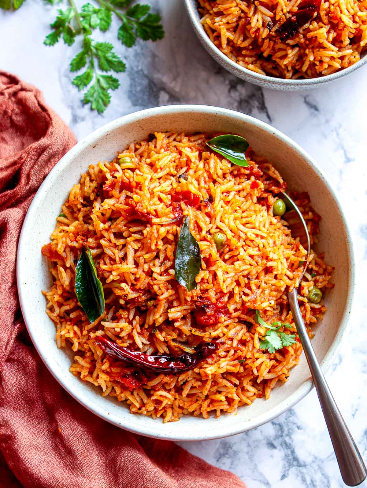 Indian spicy tomato rice with curry leaves and dried red chili in a bowl.