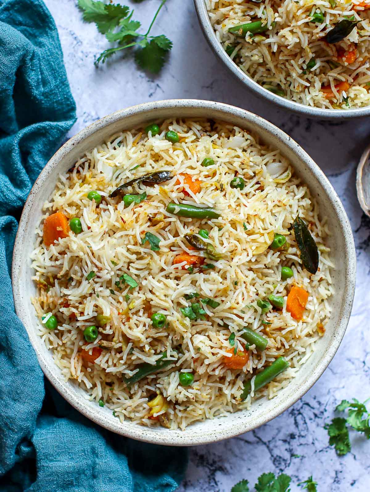 Indian vegetable pulao with basmati rice, peas, carrots, and curry leaves in a bowl.