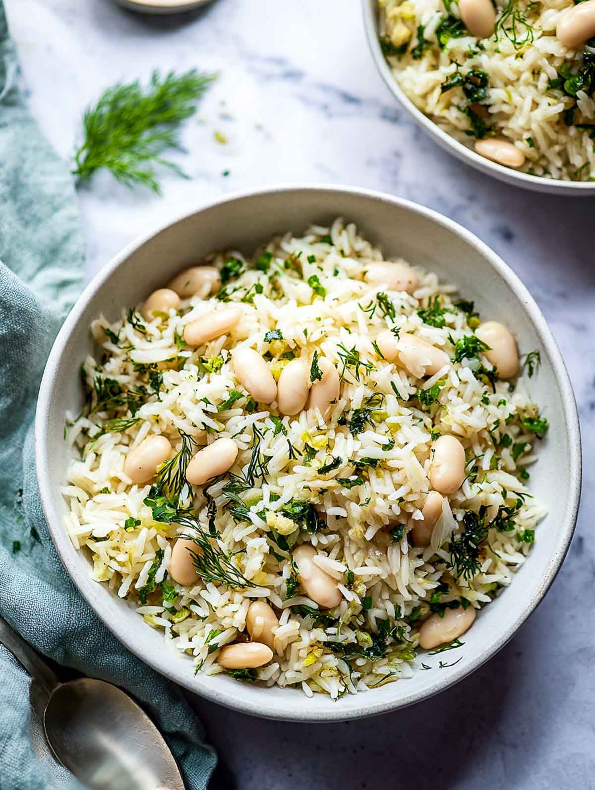 Lemon herb rice cooker white bean pilaf with dill, parsley, and garlic in a bowl.