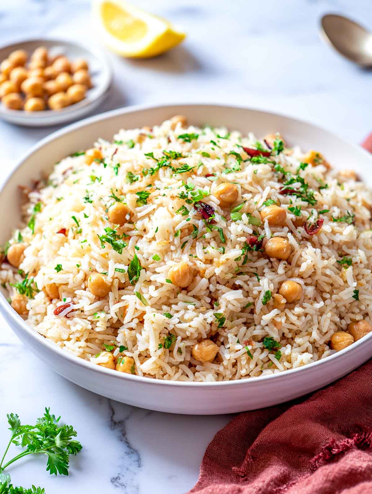 Mediterranean chickpea rice pilaf with herbs and lemon served in a white bowl.