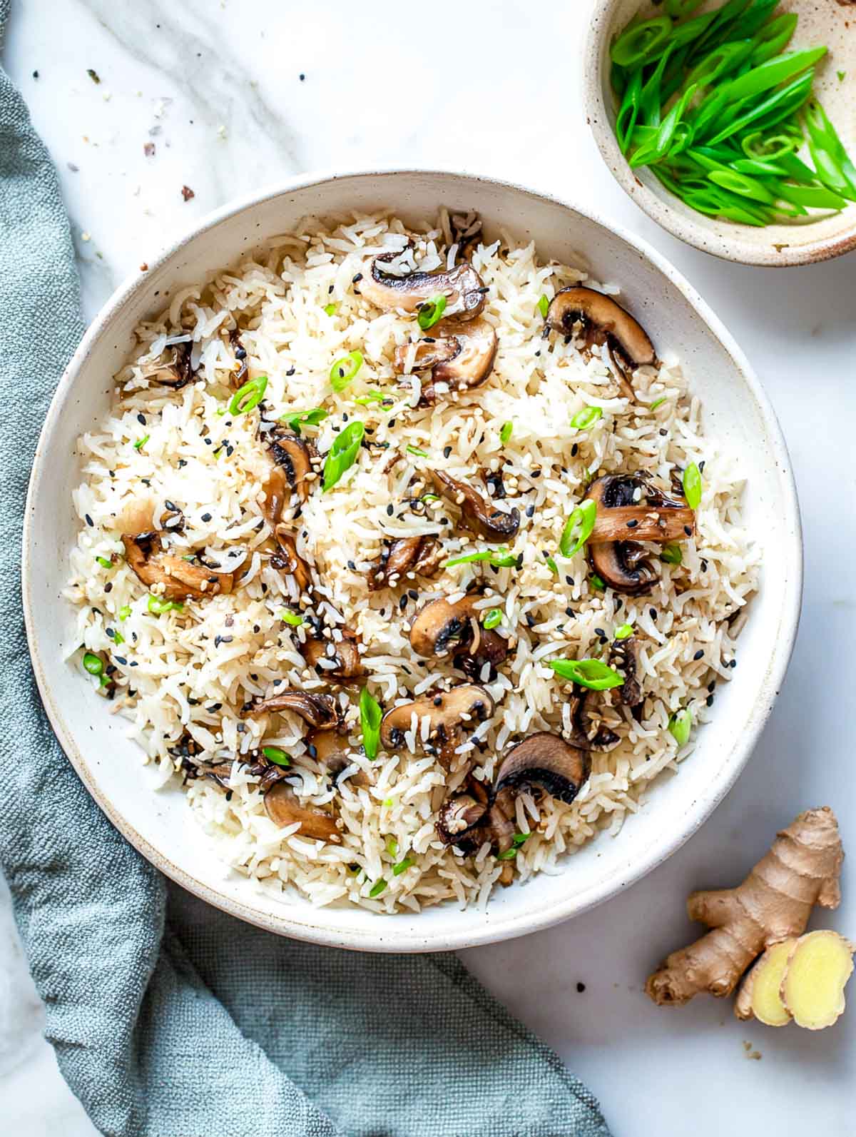 Mushroom soy ginger rice cooker rice with scallions and sesame seeds in a white bowl.