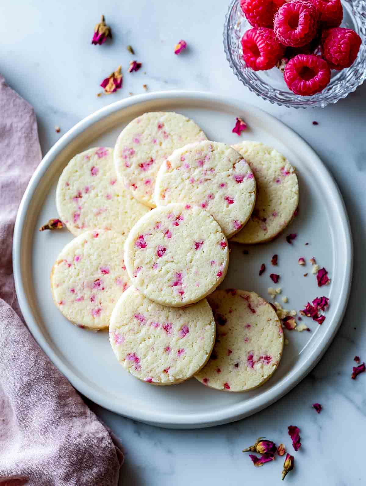 Raspberry rose shortbread cookies with pink flecks on a white plate.