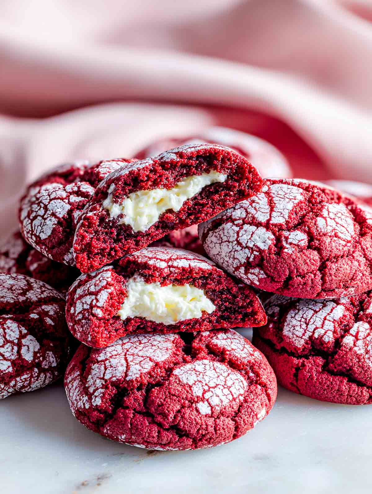 Red velvet crinkle cookies with cream cheese centers on a white plate.