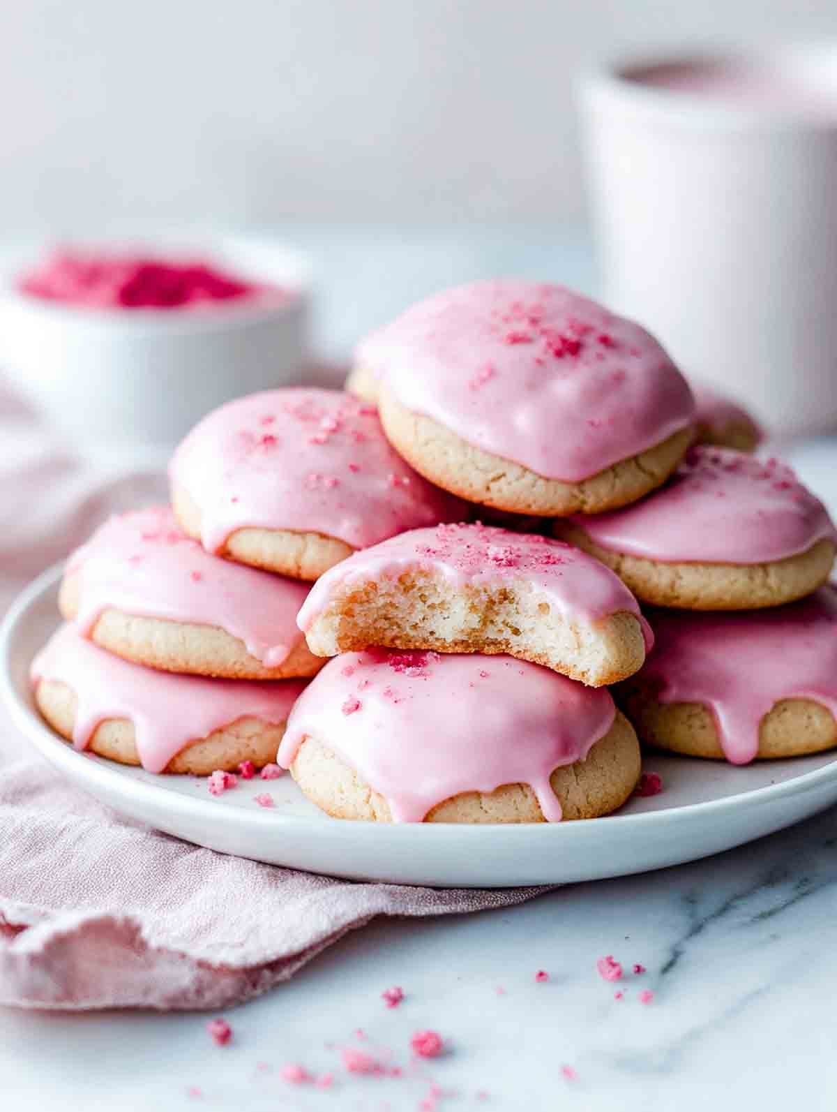 Strawberry sugar cookies with smooth pink glaze on a white plate.