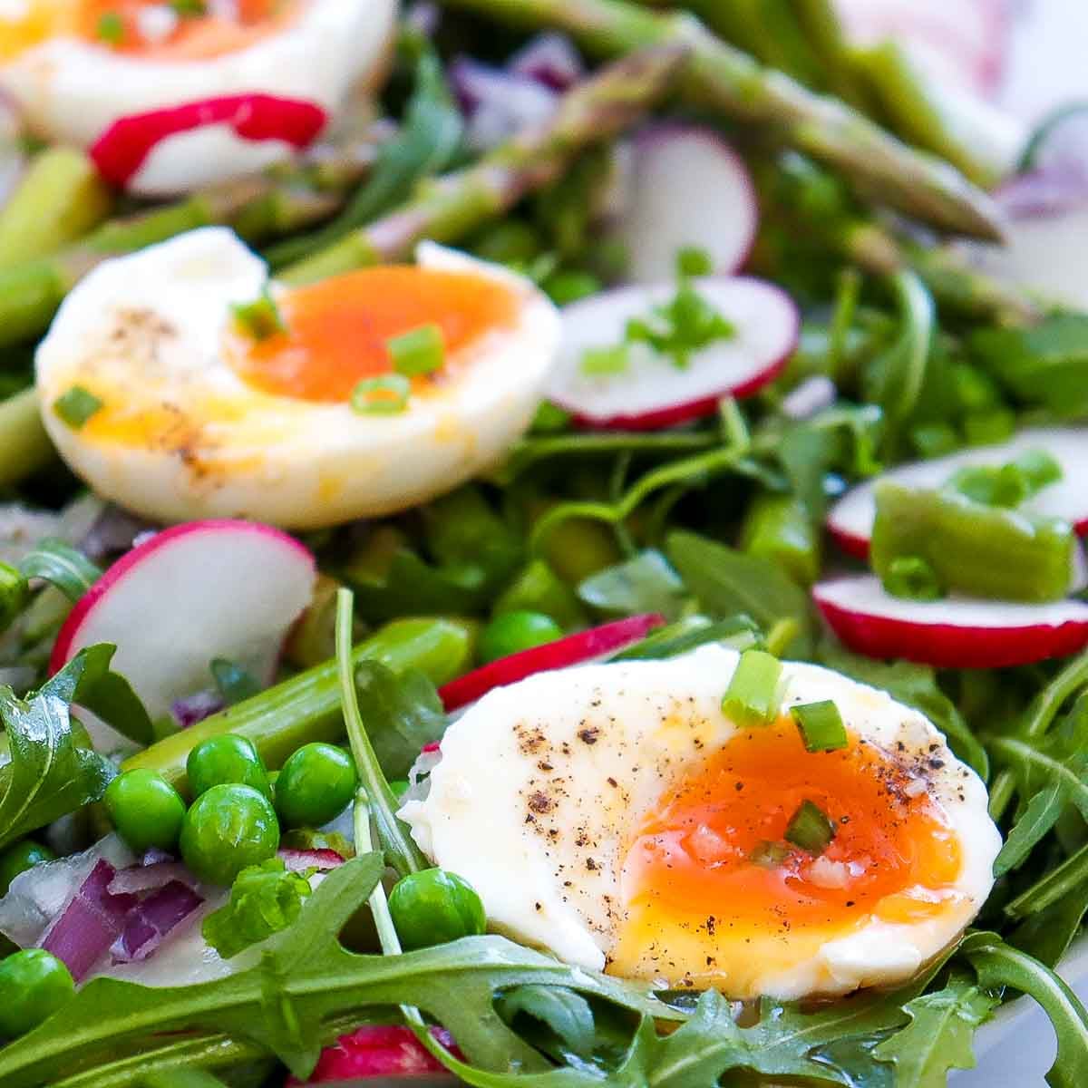 Close up of soft boiled eggs over the salad showing the texture.