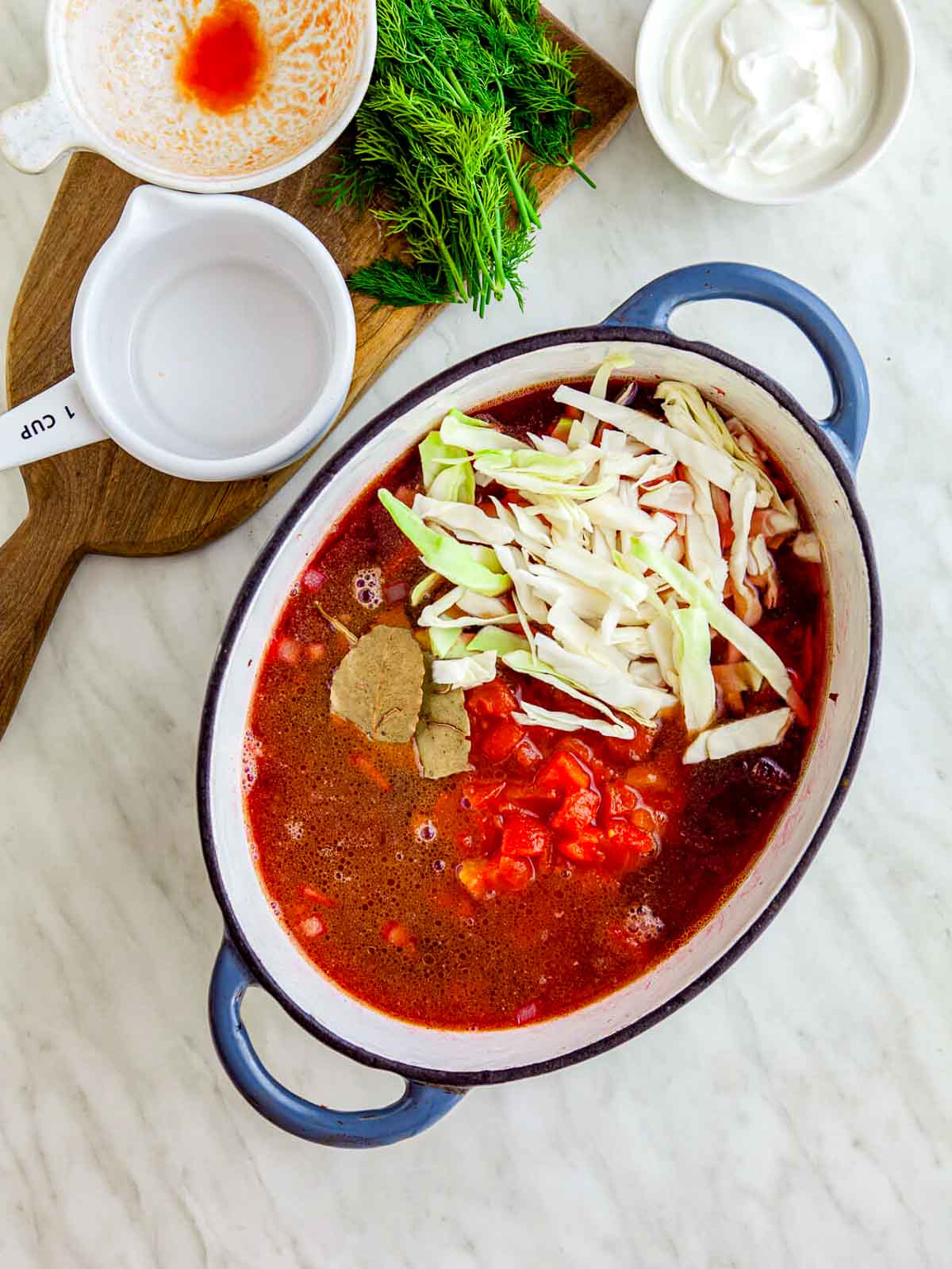 Shredded cabbage, bay leaves, and broth added to the pot with the beet mixture, ready to simmer into borscht.