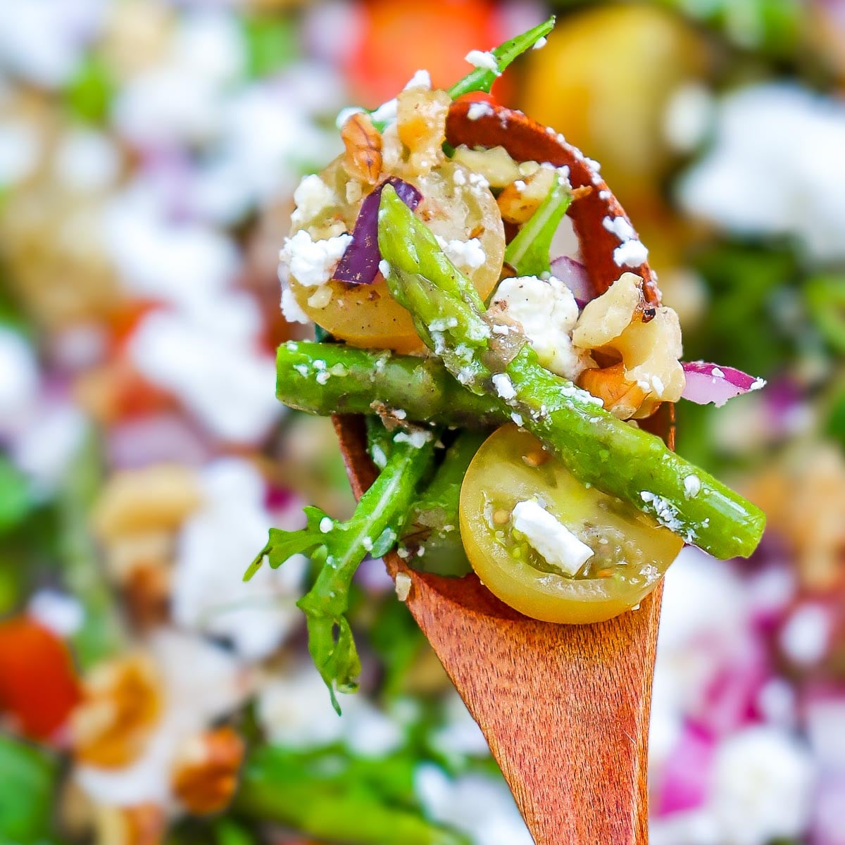 A spoonful of goat cheese asparagus salad showing different colors and textures.