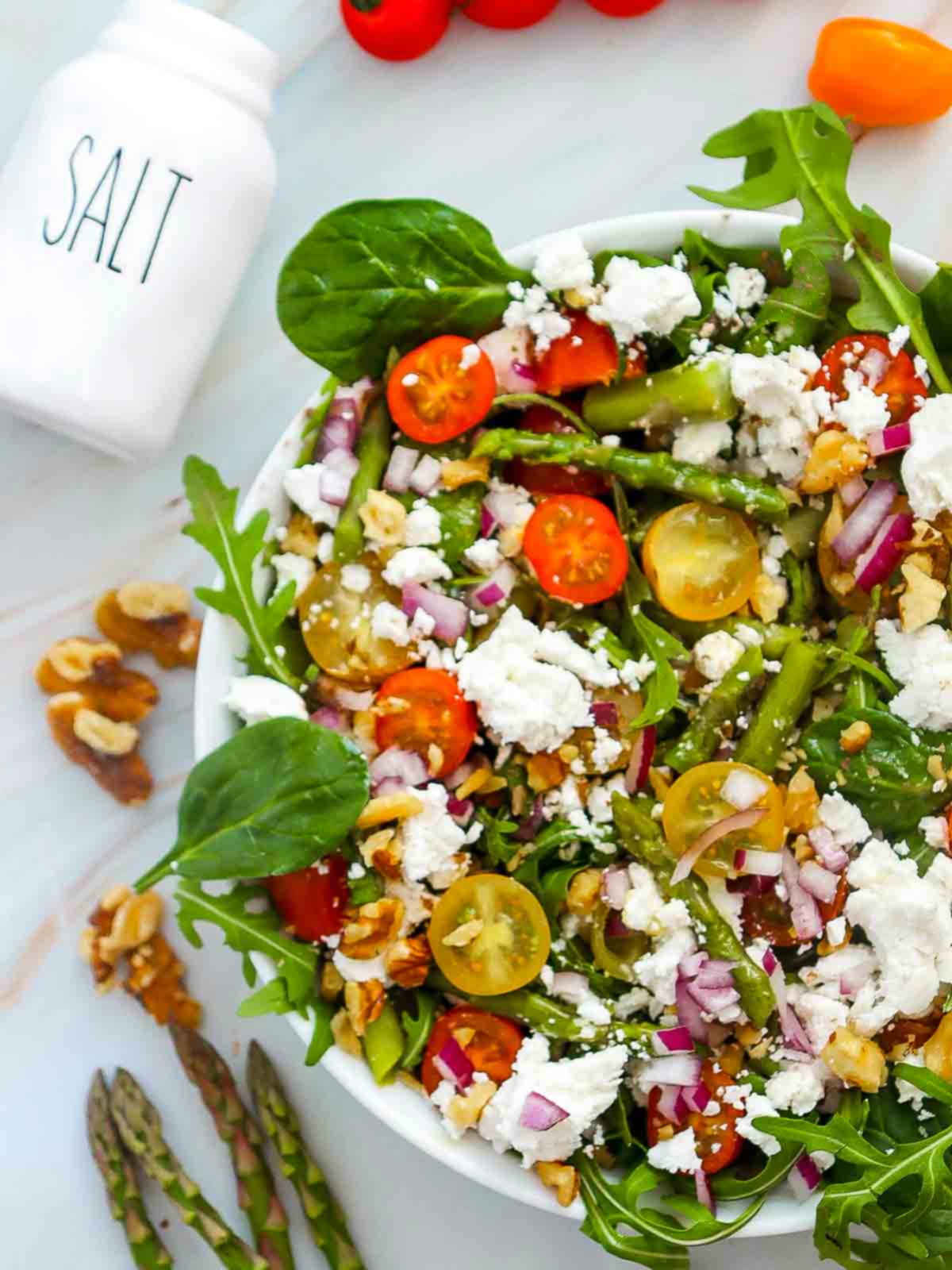 Close up of asparagus salad with a salt shaker in the background.