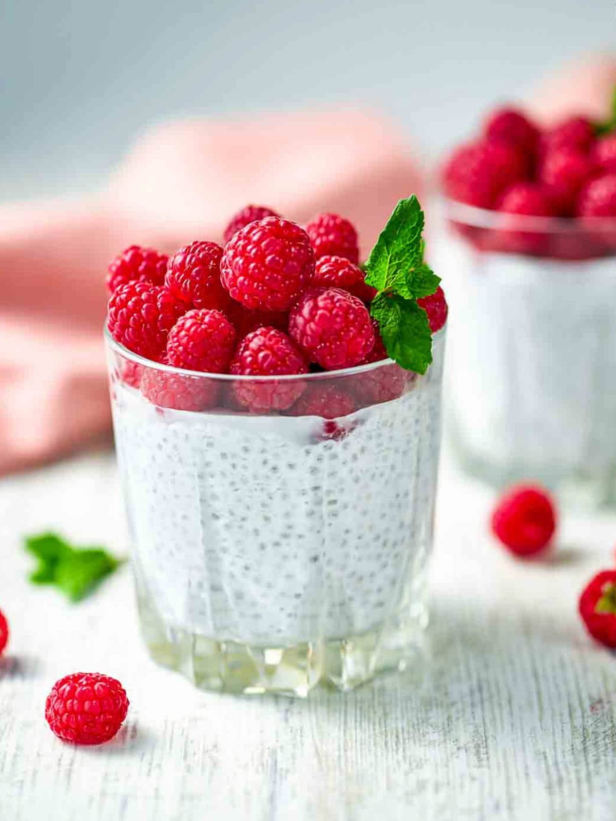 Glass of chia pudding topped with fresh raspberries and mint leaf