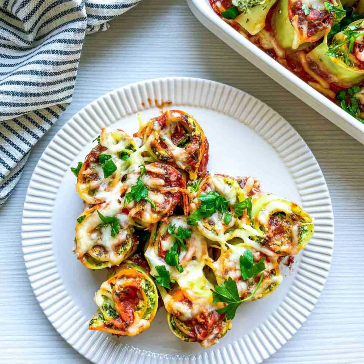 Close up of spinach ricotta lasagna roll ups served on a white plate.