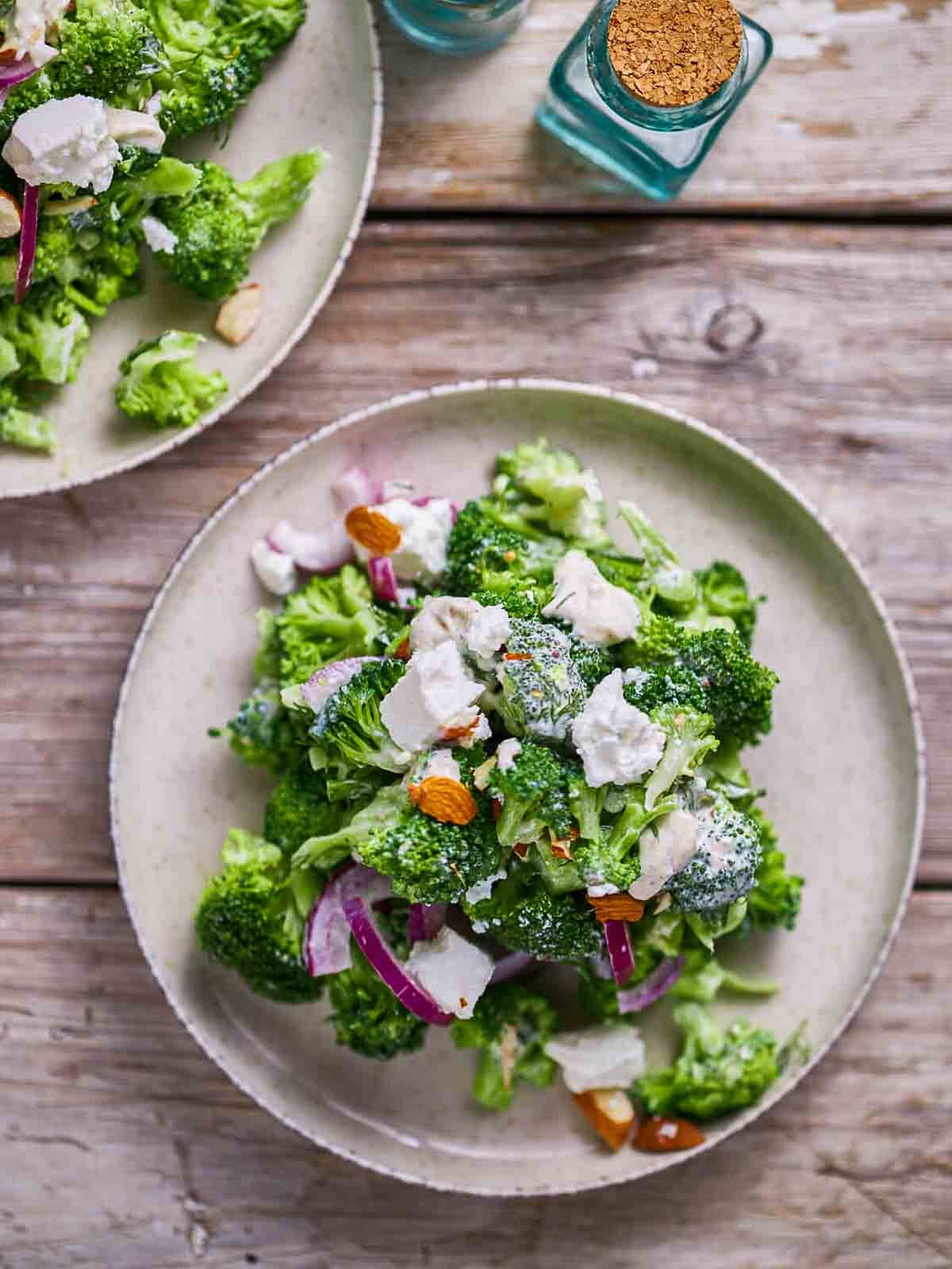 Broccoli salad with feta, red onion, and sliced almonds on a plate.