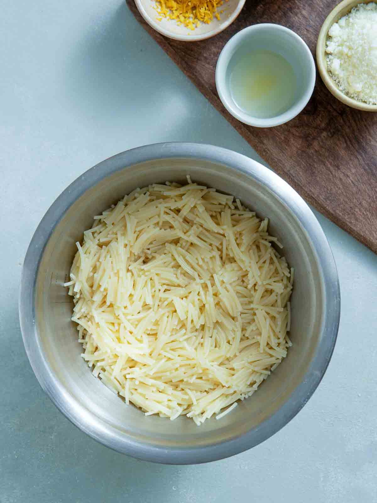 Bowl of shredded parmesan cheese for topping chicken fideo soup.