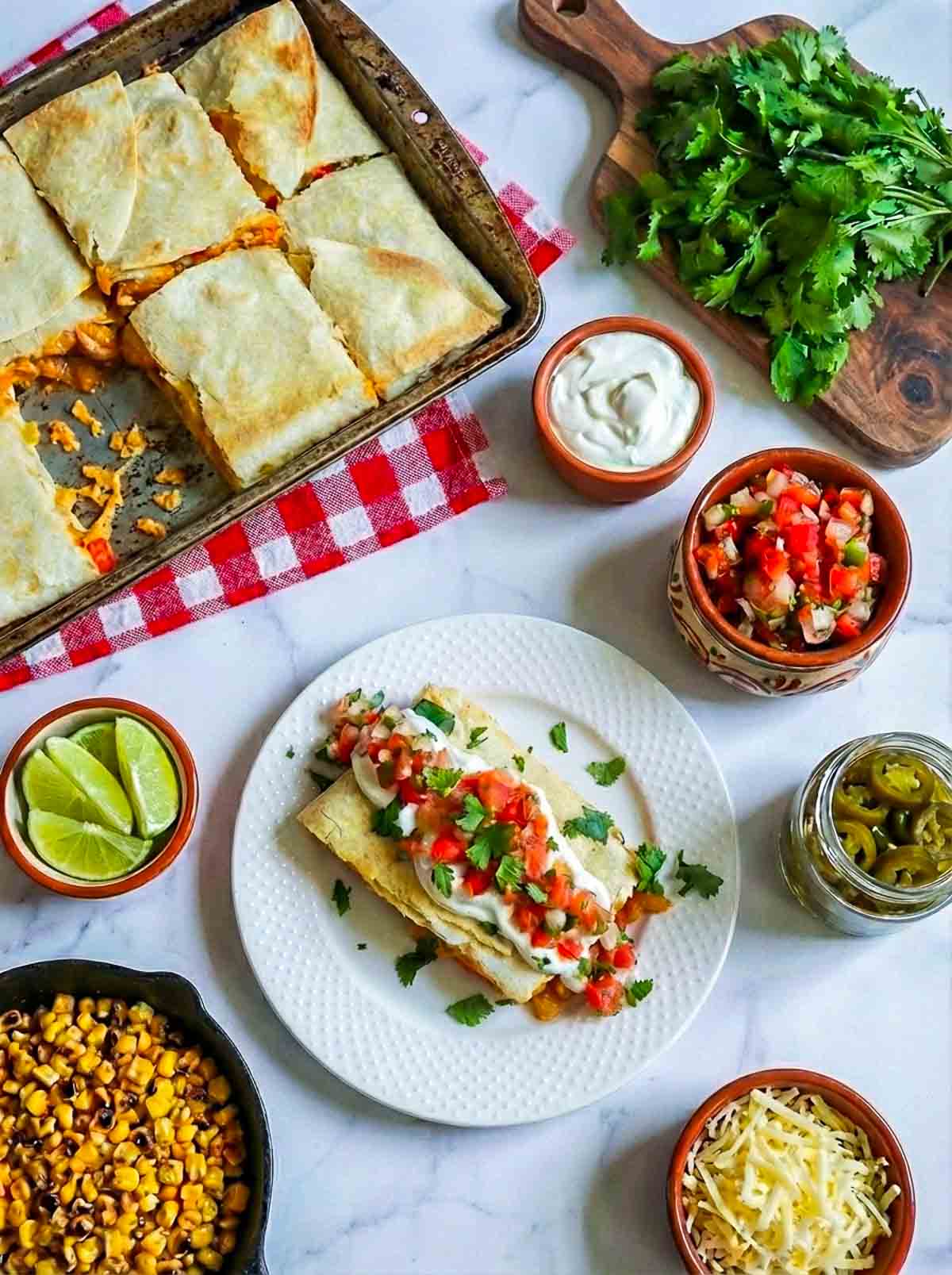 A slice of chicken fajita quesadilla on a white serving plate with the baking sheet in the background.
