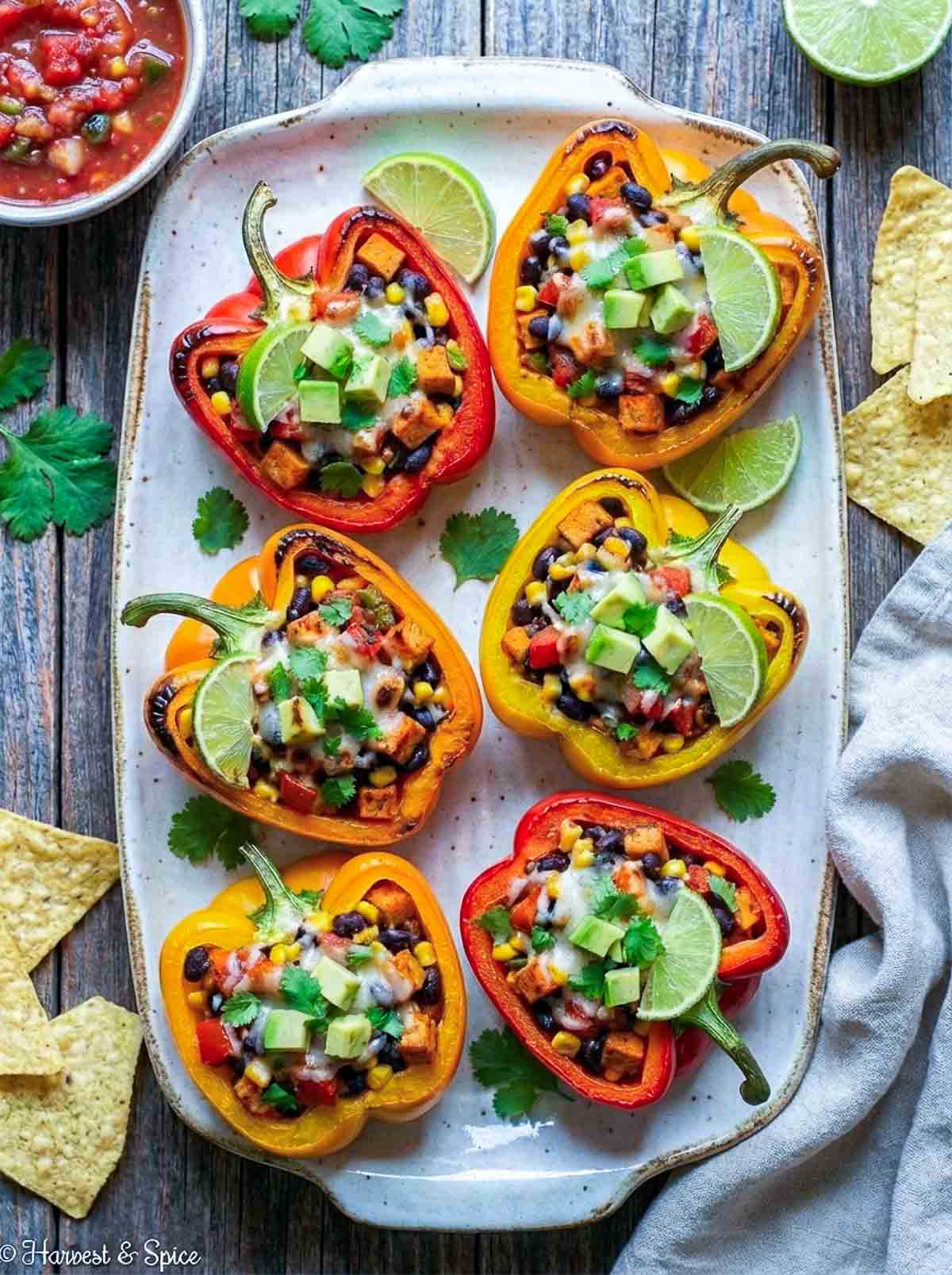 Red and yellow stuffed bell peppers placed on a white rectangular serving plate.