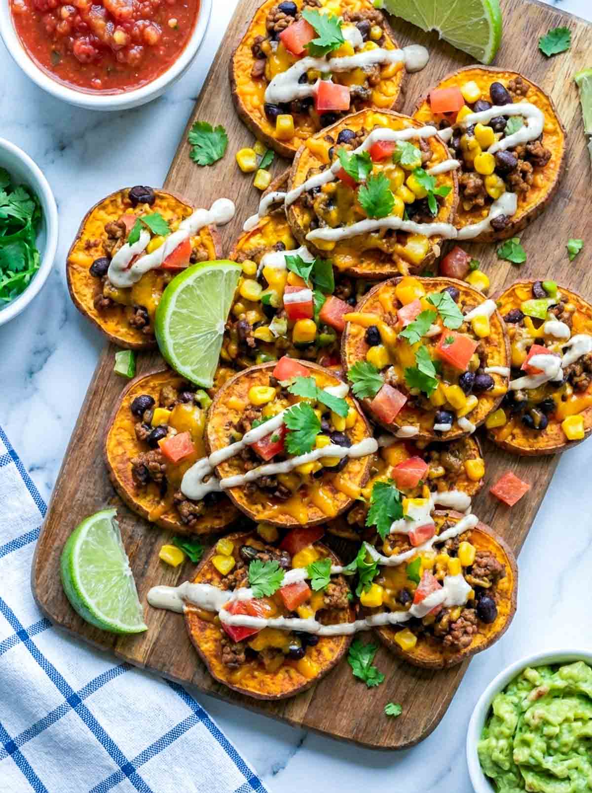 Sweet potato rounds roasted and topped with taco stuffing and served on a wooden board.